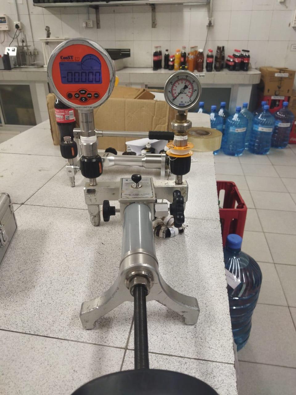 Deadweight pressure tester and digital master pressure gauge calibration apparatus on laboratory bench